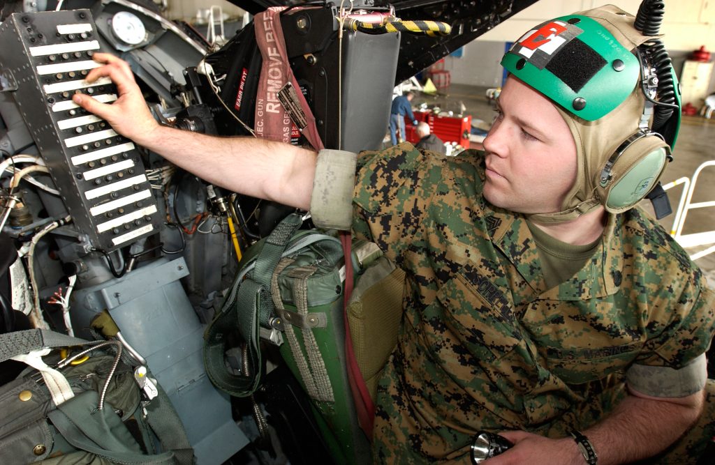 Technician inspecting circuit breakers inside an aircraft cockpit
