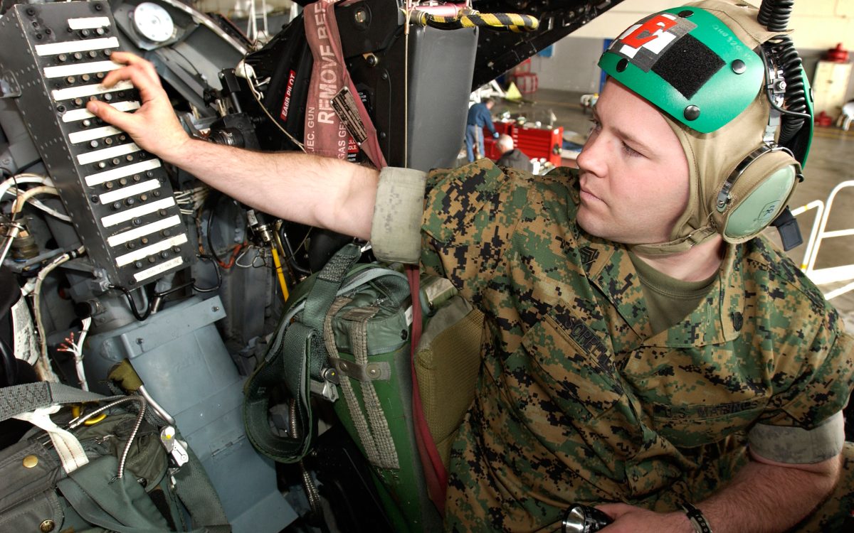Technician inspecting circuit breakers inside an aircraft cockpit